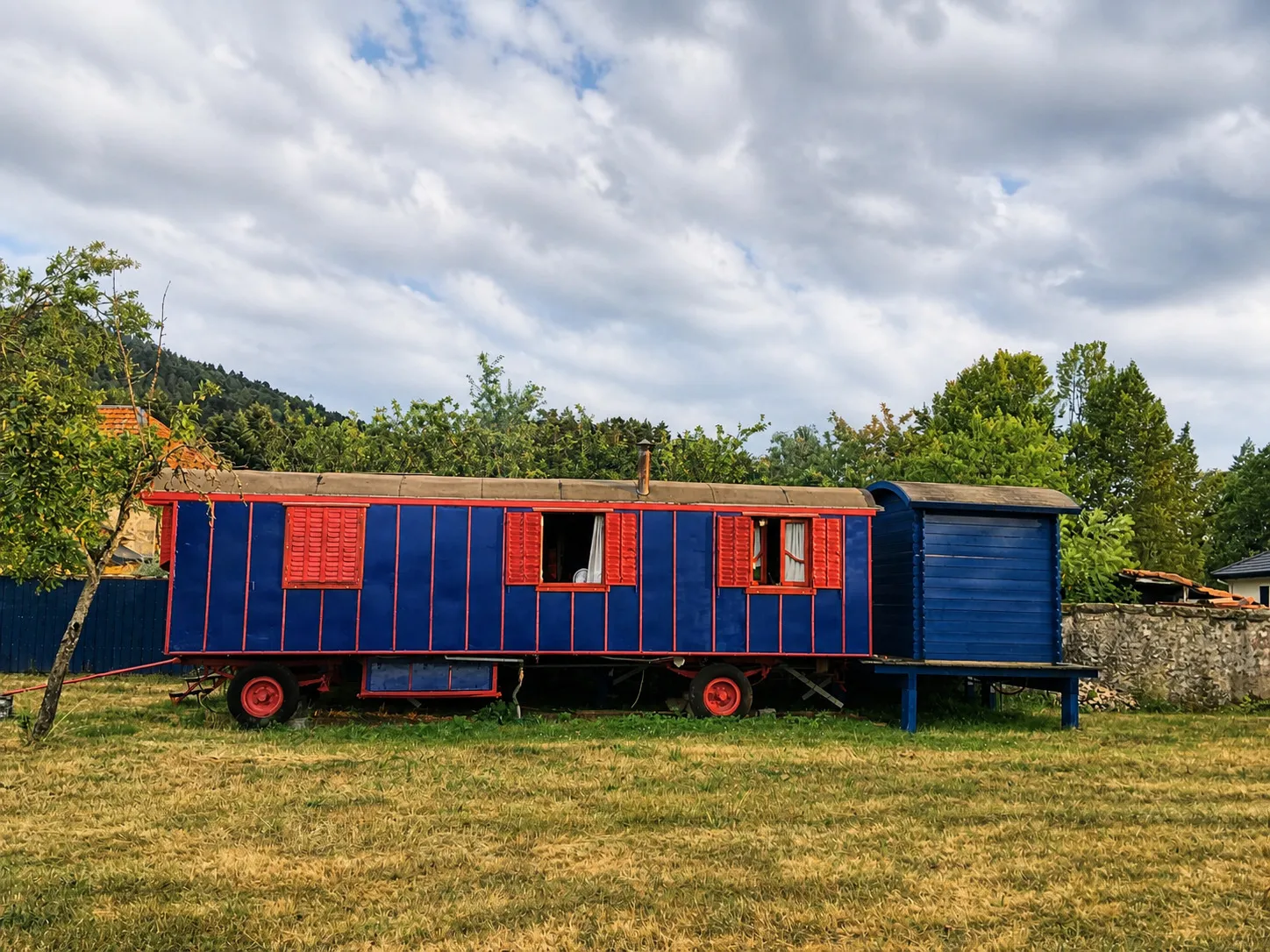 La Roulotte « Blue Lady », roulotte bleue et rouge dans le jardin
